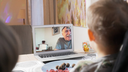 Family talking with parents on facetime video chat. Children communicating with their grandfather on webcam. Modern technology connecting people of all ages concept. 