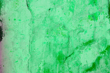 Green background. Wall with peeling plaster, tinted in green. Modern urban building concept. Bright neon backdrop. Selective focus