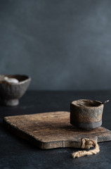 Dark handmade bowl on wooden background on black table, pottery workshop, hand crafted dish. Copy space.