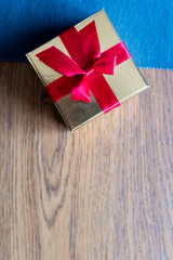 Small golden gift box with red ribbon on top. Gift for mother's day, birthday or jewellery for women. Gift box for present during special occasion