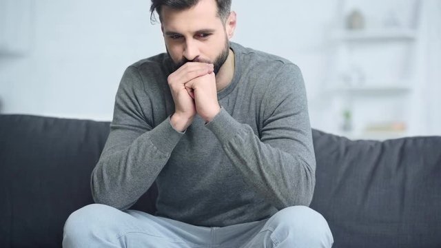 worried man sitting on sofa at home