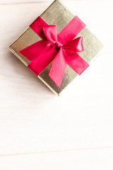 Small golden gift box with red ribbon on top. Gift for mother's day, birthday or jewellery for women. Gift box for present during special occasion