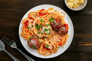 Italian meal made of pasta on a wooden table. Plate of traditional American spaghetti with meatballs and tomato sauce. Top view shot directly above.