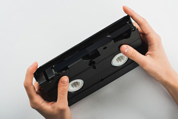 partial view of man holding old VHS cassette on white background