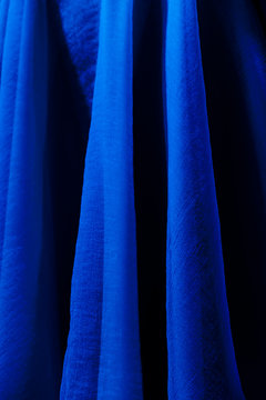 Vivid Blue Fabric Texture Background. Dark Blue Curtains Folds. Canvas Waves. Vertical, Close Up