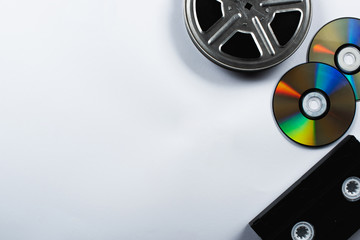 top view of CD discs, VHS cassette and film reel on white background