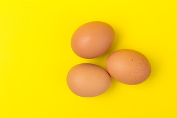 Brown eggs close up, isolated on yellow background. space for text