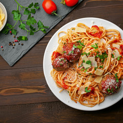 Delicious spaghetti pasta with meatballs and tomato sauce on a plate. Traditional American Italian food on a rustic wooden table. Top view shot directly above.