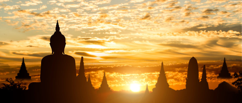 Silhouette of Buddha on golden temple sunset background. Travel attraction in Thailand.