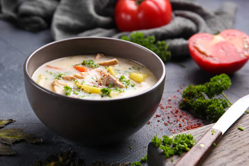 Finnish soup with salmon, potatoes, carrots, tomatoes and cream in a deep gey bowl. Parsley,...
