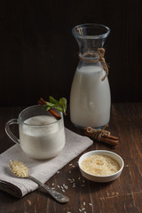 Rice vegetable milk in a Cup, a jug and white rice in a plate and a small spoon, vertically
