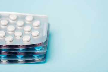 Close up view of hormonal pills in blisters on blue background
