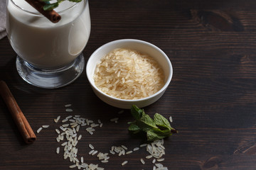 Rice milk without animal fat in a glass and a plate with white rice, top view with space