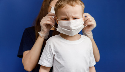 Doctor or nurse puts a protective mask on the little boy. Personal protective equipment against...