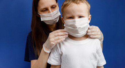 Doctor or nurse puts a protective mask on the little boy. Personal protective equipment against...