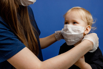 Doctor or nurse puts a protective mask on the little girl. Personal protective equipment against...