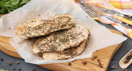 Chicken fillet with aromatic herbs on parchment on a wooden board, healthy nutrition