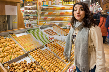 Beautiful traveler woman looks at traditional Turkish dessert Baklava sold in Egyptian bazaar in Istanbul,Turkey.Traveler woman lifestyle Concept.