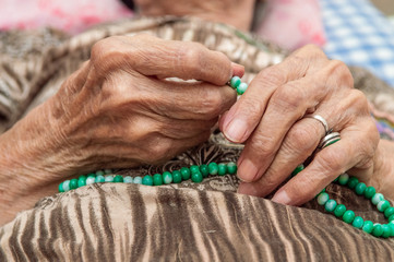 Old female hands holding green praying beads