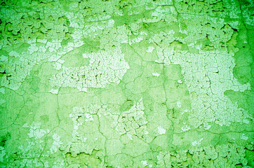 Fragment of old house wall close-up. Green background. Peeling plaster on concrete surface. Cracks in paint. Copy space. Place for text. Selective focus image.