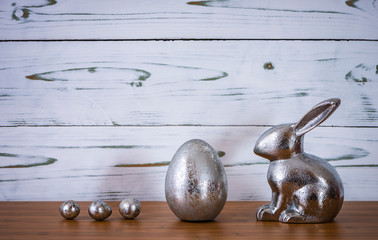 Ein Osterhase mit einem großen Osterei und drei kleine Ostereier vor einem Holz Hintergrund