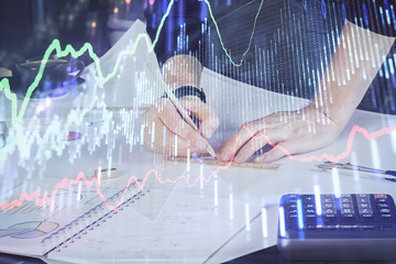 Double exposure of man writing on paper with forex graph.