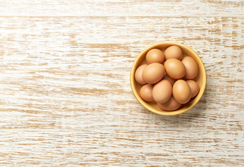 Bowl with  organic chicken eggs  on a white wooden table, top view.