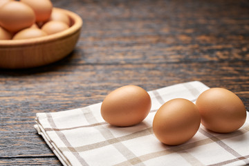 Organic chicken eggs in a wooden bowl on a kitchen table, with copy space.