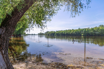 Flooded sunny landscape of beach with overflow level of water of spring river.