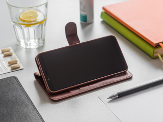 Distance learning or work, online education concept. Workplace. Smartphone, books, glass of water with lemon and pills on the table. Phone screen mockup