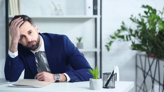 frustrated businessman in suit sitting in office