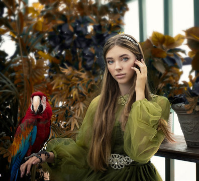 Art photo of a young fairy nymph with a red macaw parrot among the yellowed foliage