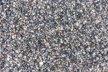 Top view flatlay photography of many colorful small stones laying on ground on sea beach. Organic abstract photo background.
