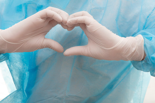 Medical Worker Shows A Heart Gesture. White Latex Gloves, Blue  Bathrobe.