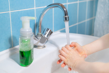 child washes his hands with liquid antibacterial soap