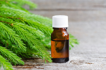 Small bottle with essential fir oil and fir branch. Aromatherapy and spa ingredients. Old wooden background. Copy space