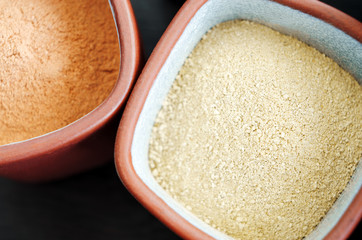 Yellow bentonite powder in the bowl. Kaolin texture, close up. Homemade beauty treatment. Top view, copy space.