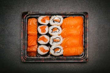 Stock photo of maki, uramaki, futomaki sushi in recycle tray on black natural slab background.
