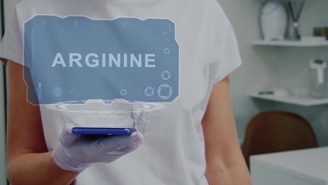 Doctor in medical glove against background of doctor's office with HUD hologram text Arginine. Hand holds futuristic holographic gadget. Medical technology concept of the future
