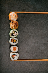 Stock photo of maki sushi stacked between two chopsticks with black background. © REFLEJAARTE 