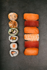 Stock photo of maki sushi stacked on one side and another stack of nigiri on the other side with black background.