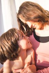 Portrait of a child hugging a mother, a boy spends time with mom, a woman gently hugs her son.