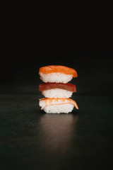 Stock photo of nigiri sushi stacked with a black background.