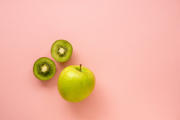 Green apple and kiwi on a pink background