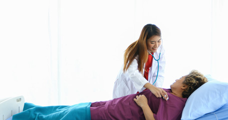 Naklejka premium The doctor used a stethoscope to check the lungs of the elderly woman at the hospital.