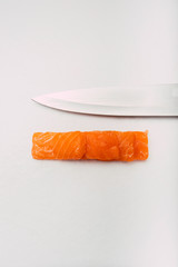 Stock photo of sashimi stacked with knife edge on top. All on white background in overhead view.