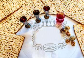 Unleavened bread food - matzah, silver cups of red wine for Jewish Passover Holiday. White...