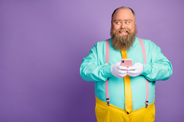 Portrait of positive gentleman blogger with big belly use cellphone enjoy texting typing social media feedback wear turquoise pink pants trousers shine isolated over violet color background