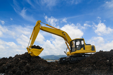 Yellow excavators are digging the soil in the construction site on the blue sky  background