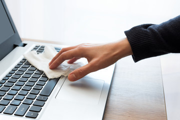 Female hand wipe laptop keyword with disinfectant napkin. Pandemic and disinfection of accessories...